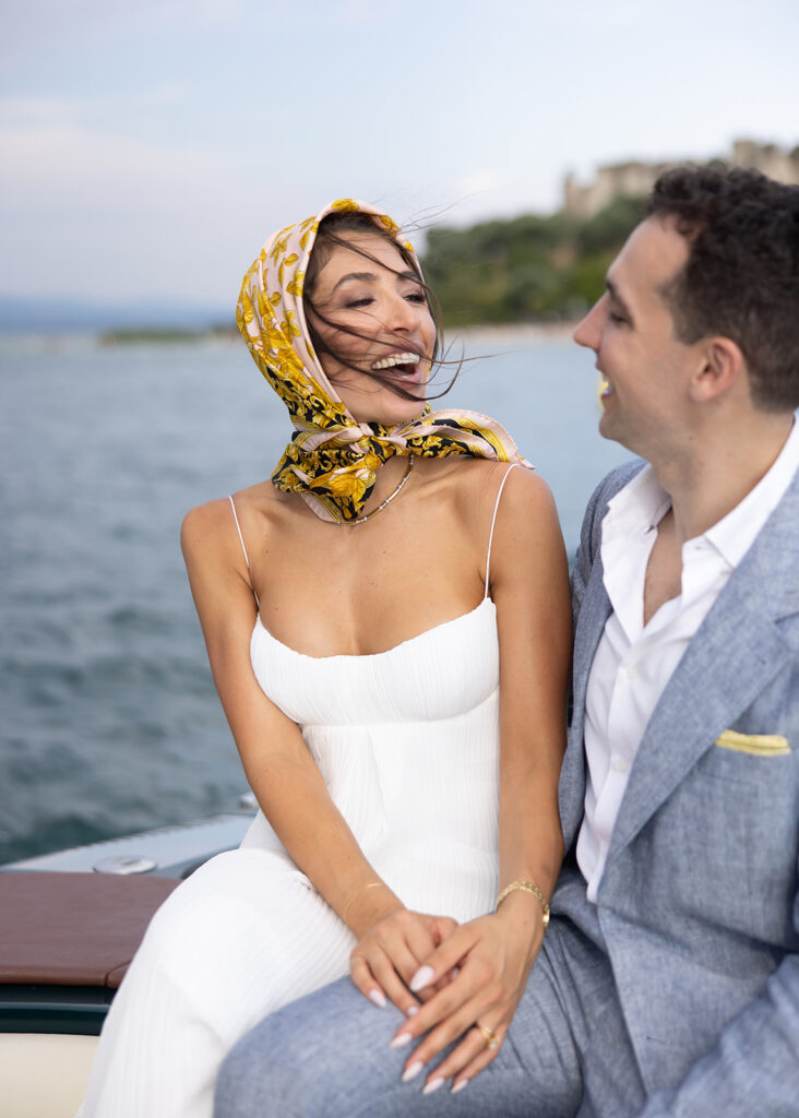 A newly married couple sitting at the bow of a speedboat on an Italian lake